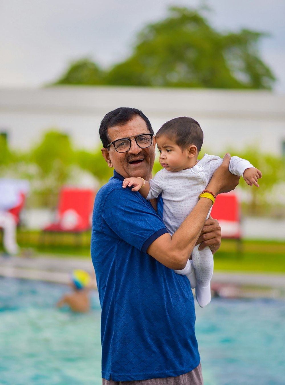 boy in blue shirt carrying baby in white onesie