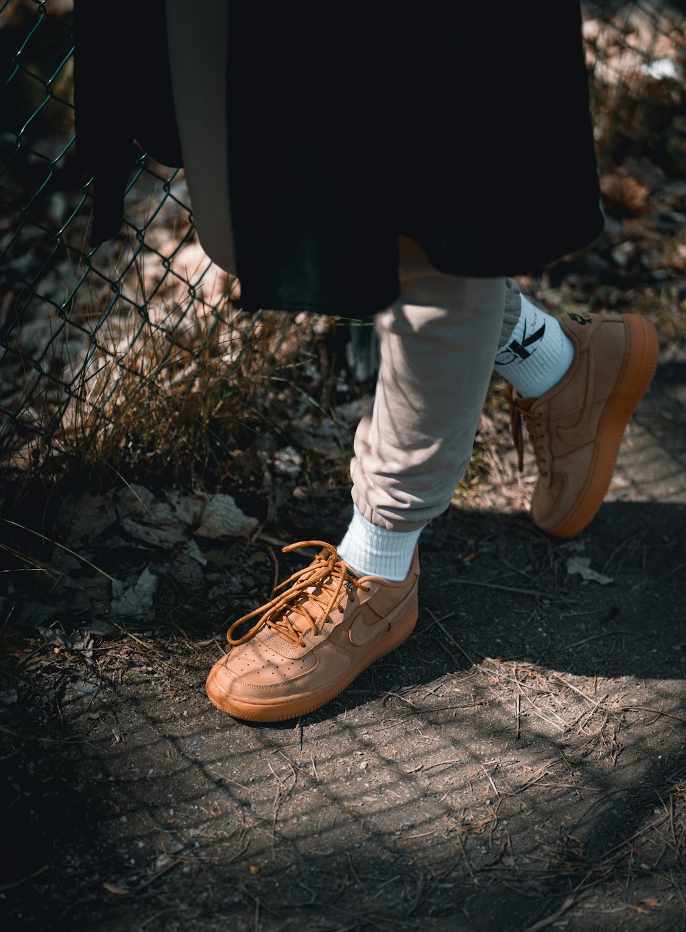 person in white pants and brown shoes standing on brown soil