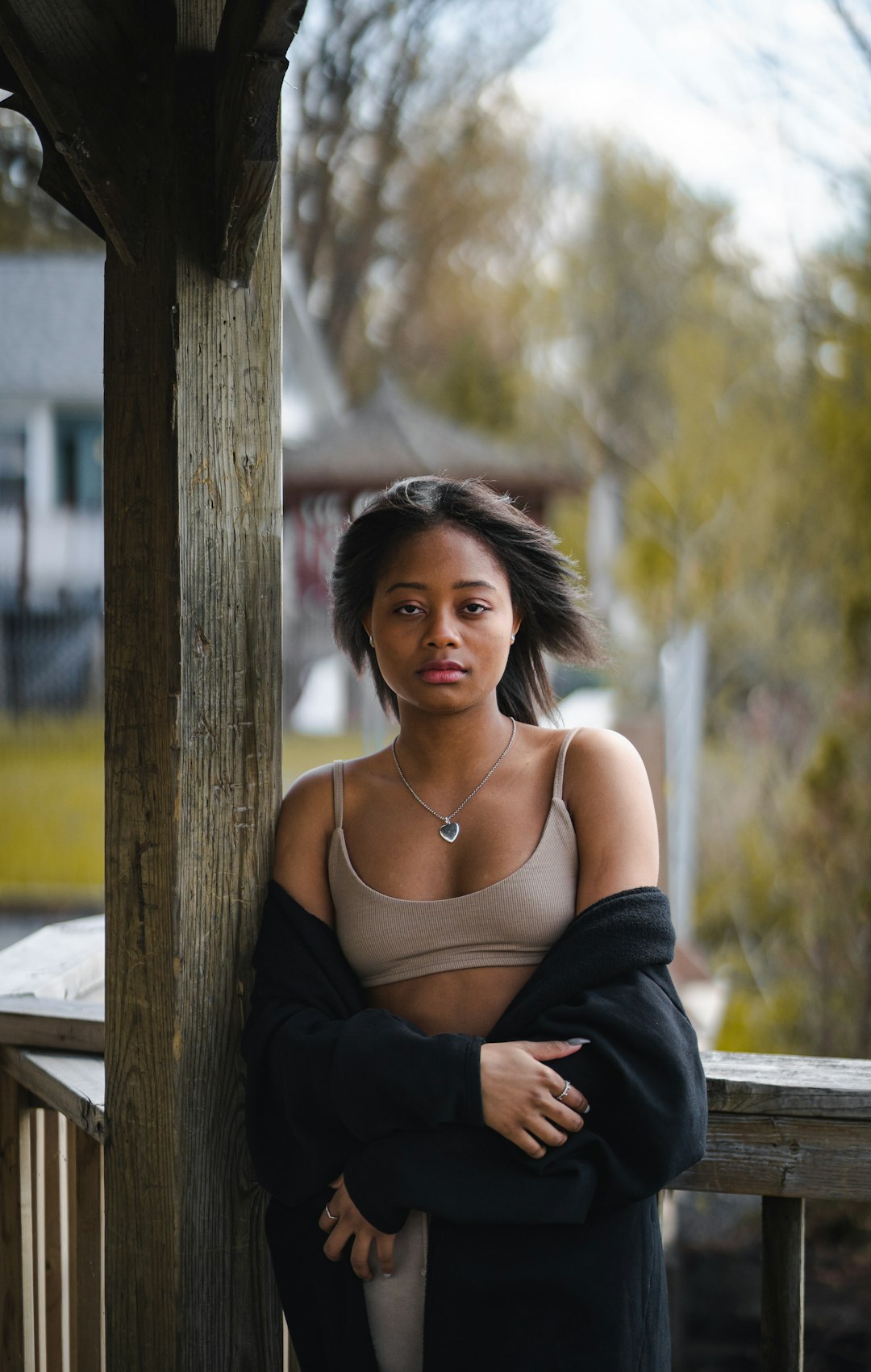 woman in black spaghetti strap top leaning on brown wooden post during daytime