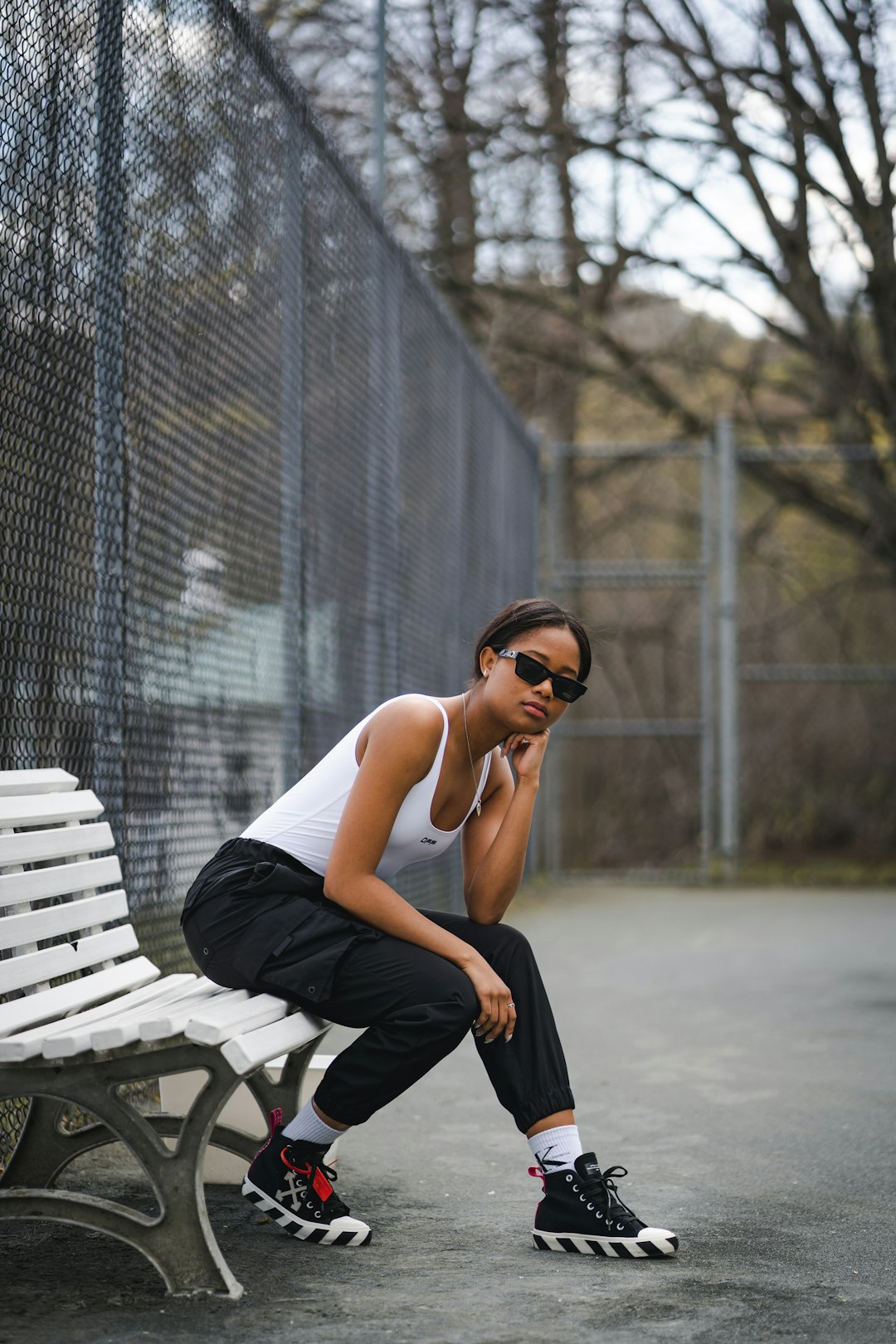 woman in white tank top and black pants sitting on white bench