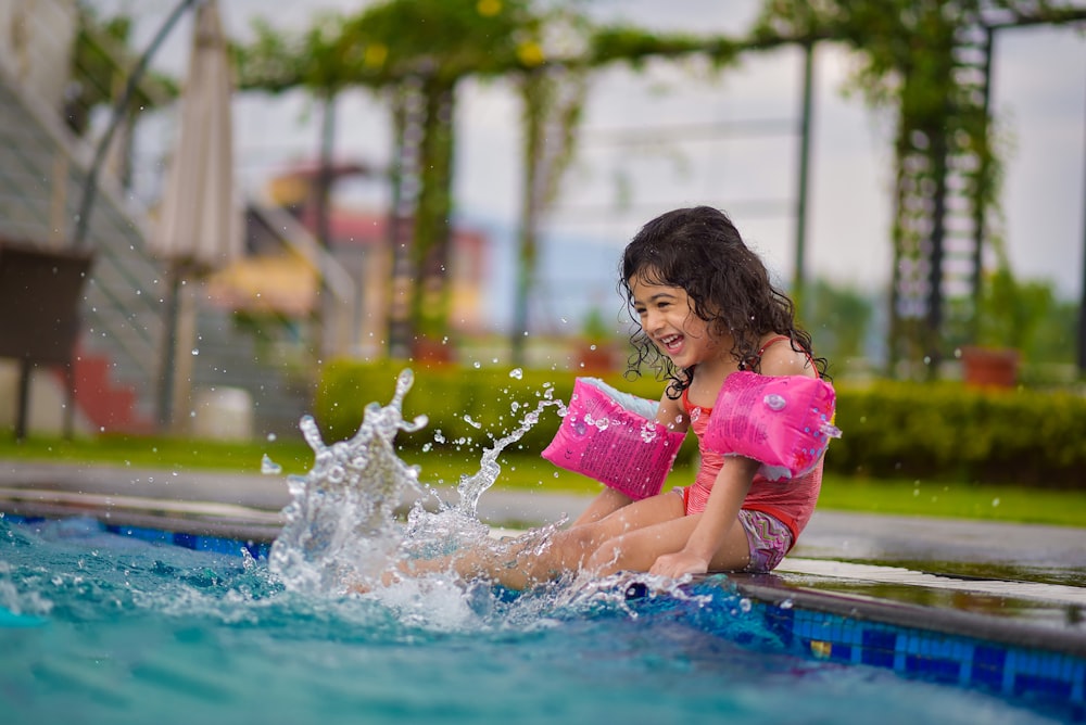 menina na camisa cor-de-rosa na piscina durante o dia