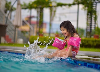 girl in pink shirt on swimming pool during daytime