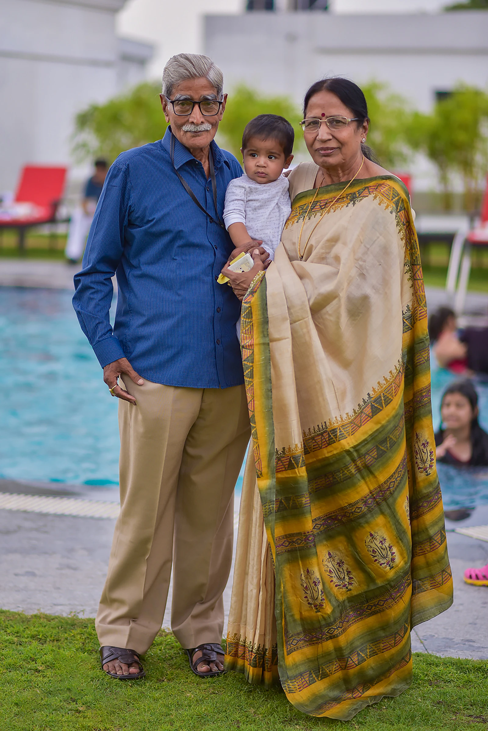 An Indian couple at home, the woman wearing a yellow and green sari