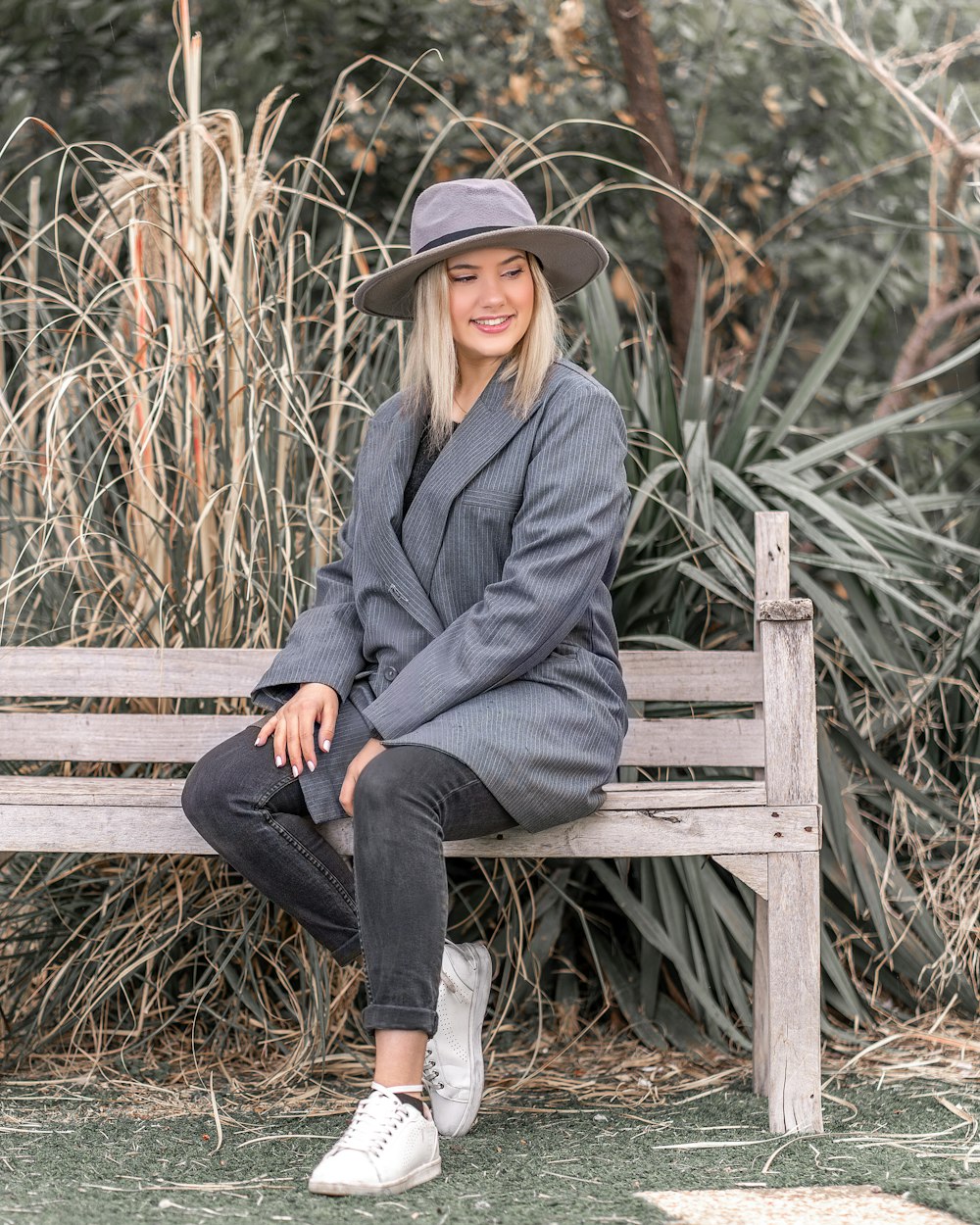 woman in gray coat sitting on brown wooden bench