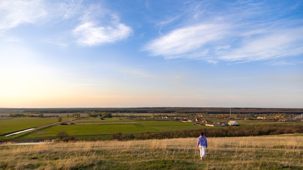 person in white shirt walking on green grass field during daytime