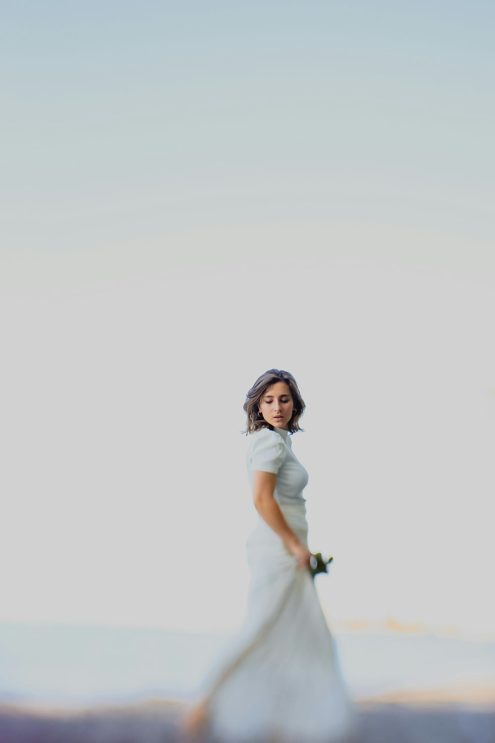 woman in white t-shirt and white pants holding black and white stick