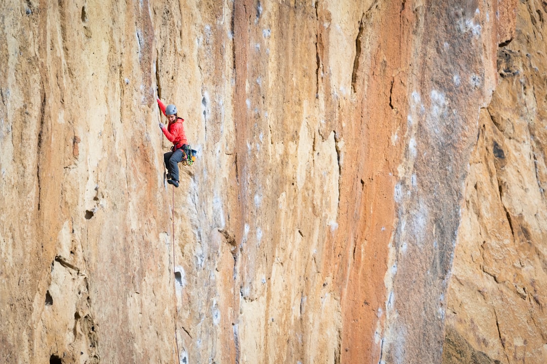 woman in red jacket and black pants climbing on brown wall, Care Bilo climbing the route Nine Gallon Buckets on Morning