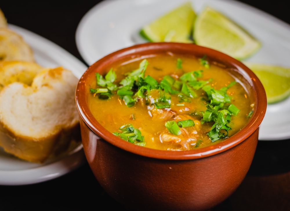 brown soup with green leaf vegetable in brown ceramic bowl