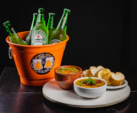 green glass bottle beside brown and white ceramic bowl with food