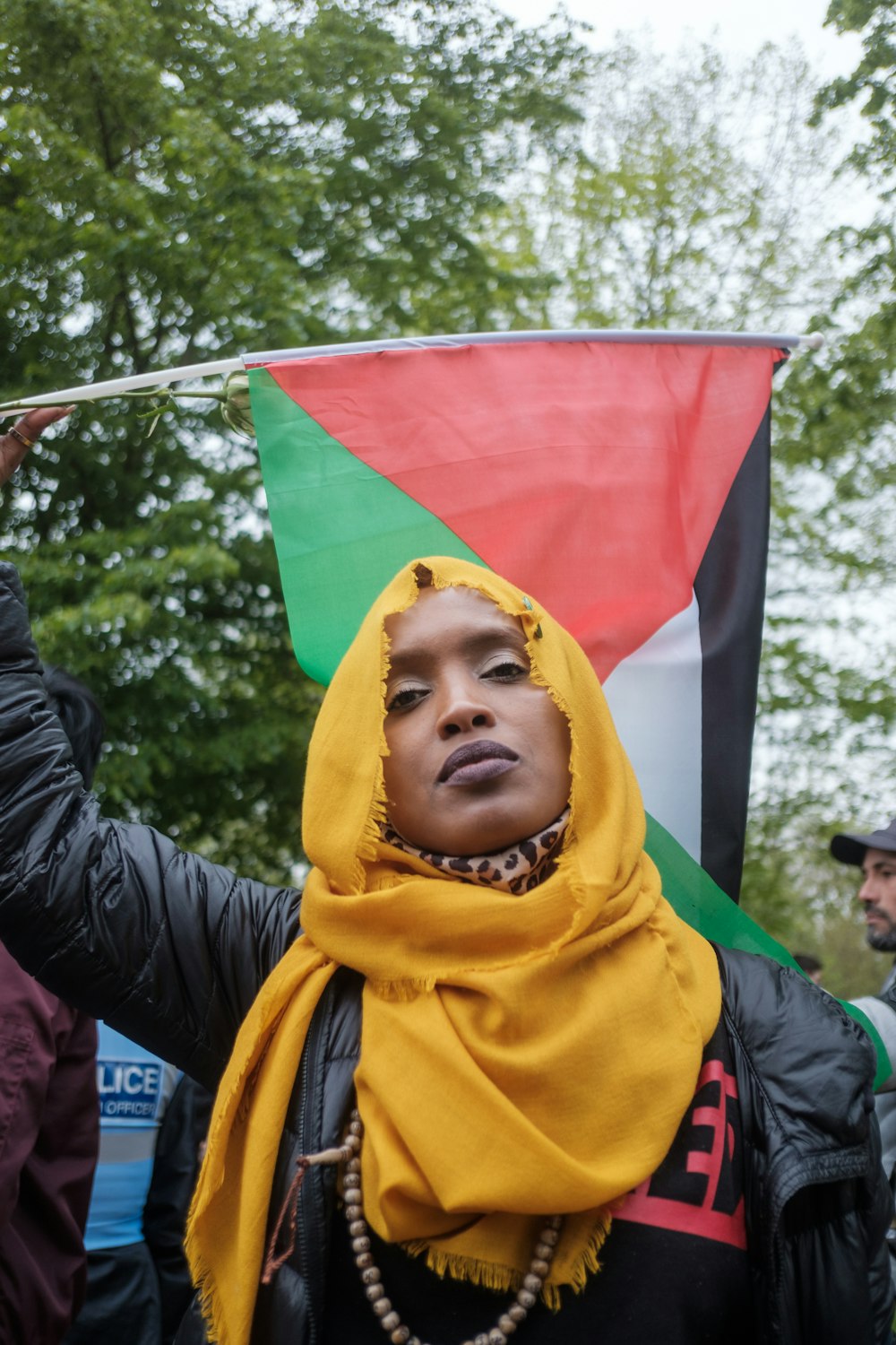 赤と黄色の旗を持つ黄色いヒジャブの女性