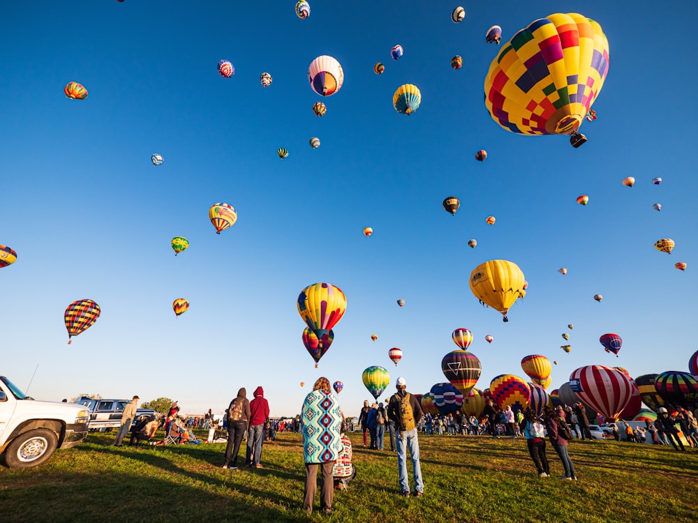 balões de ar quente no campo de grama verde sob o céu azul durante o dia