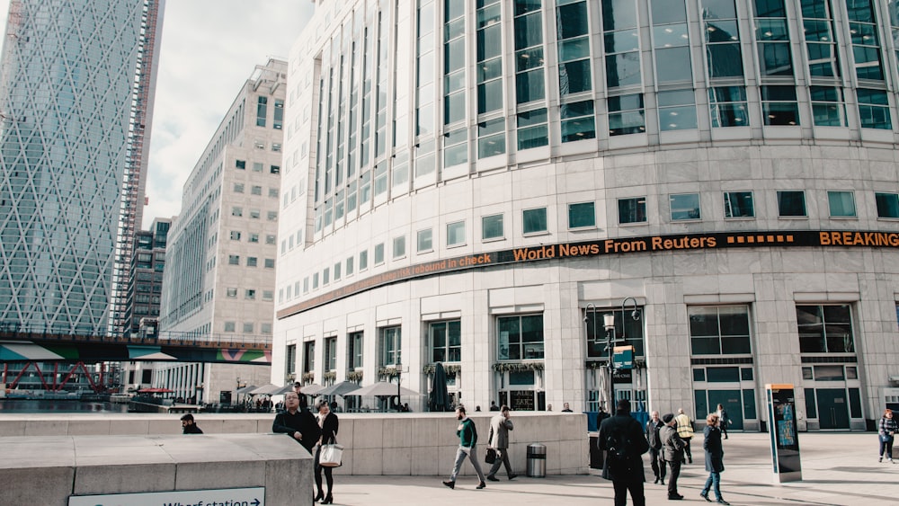 people walking on sidewalk near white concrete building during daytime