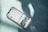 A smartphone displaying an Instagram profile screen lies on a textured teal surface with sunlight casting dappled shadows over the scene. The phone case appears clear with a slight reflection.