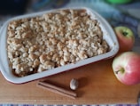 Close-up of a golden apple crumble with a crispy topping in a rustic ceramic dish.
