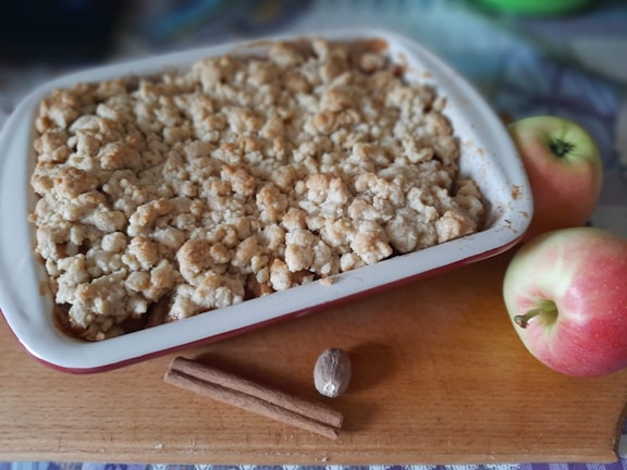 Close-up of a golden apple crumble with a crispy topping in a rustic ceramic dish.