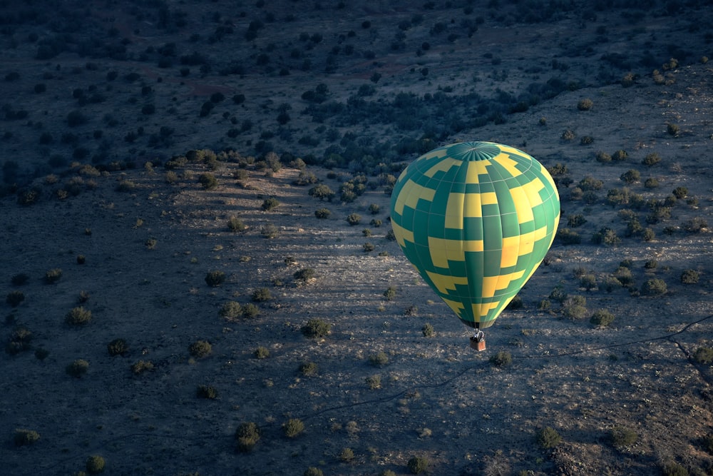 a green and yellow hot air balloon in the middle of a desert