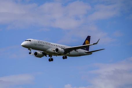 A commercial airplane with the Lufthansa Regional branding flies against a backdrop of a mostly clear sky with a few clouds visible.