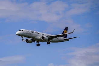 A commercial airplane with the Lufthansa Regional branding flies against a backdrop of a mostly clear sky with a few clouds visible.