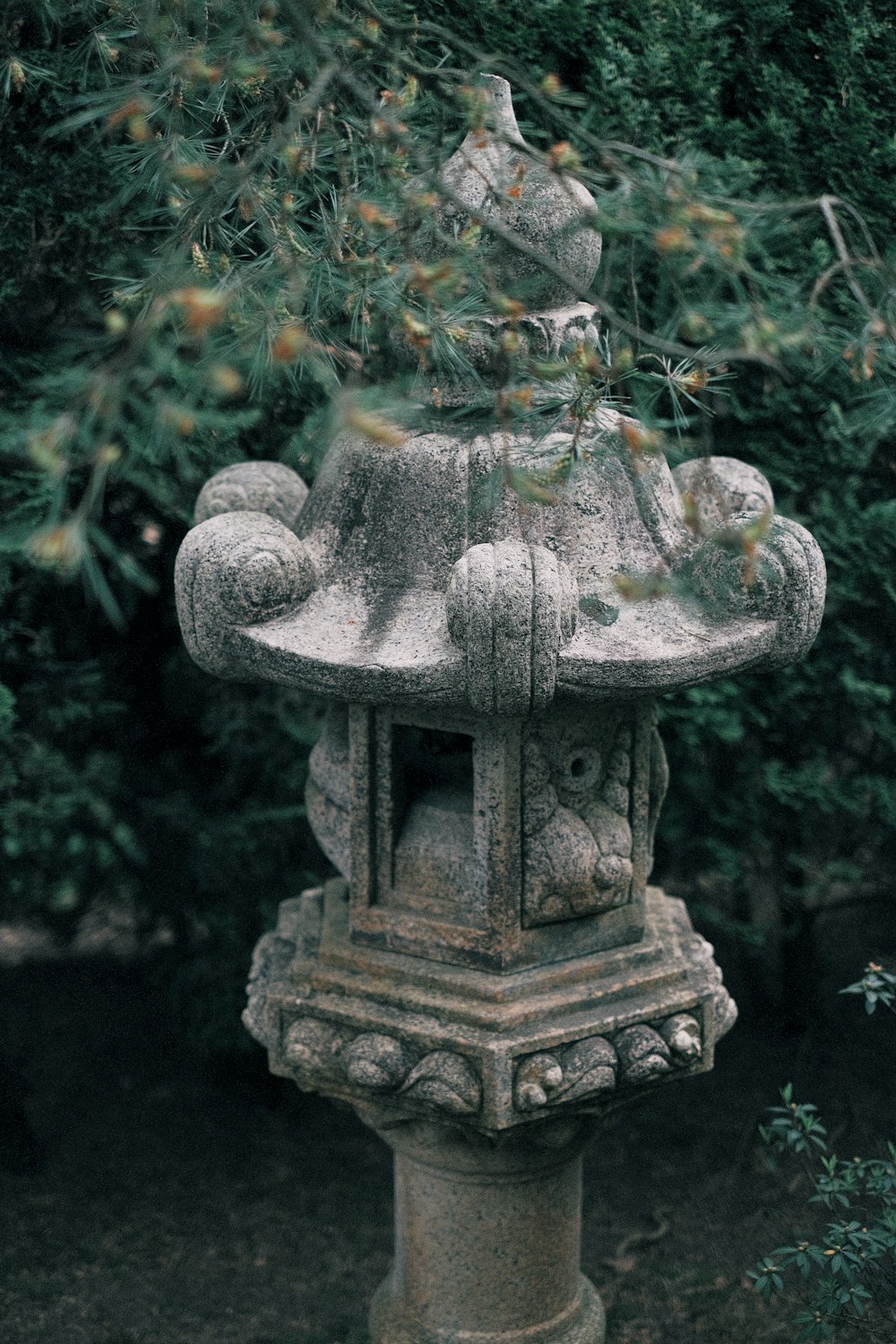 gray concrete statue surrounded by green leaves