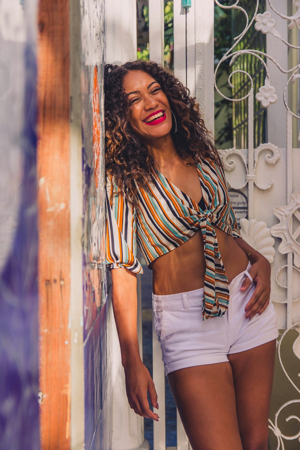 woman in white and black stripe crop top and white denim shorts standing beside brown wooden