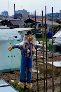 A kid-friendly scarecrow with a big smile standing guard by the garage door, wearing a colorful hat.