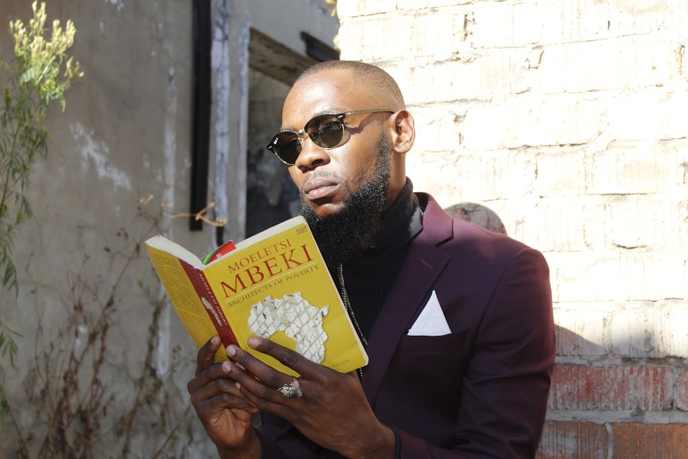 man in black suit holding yellow book