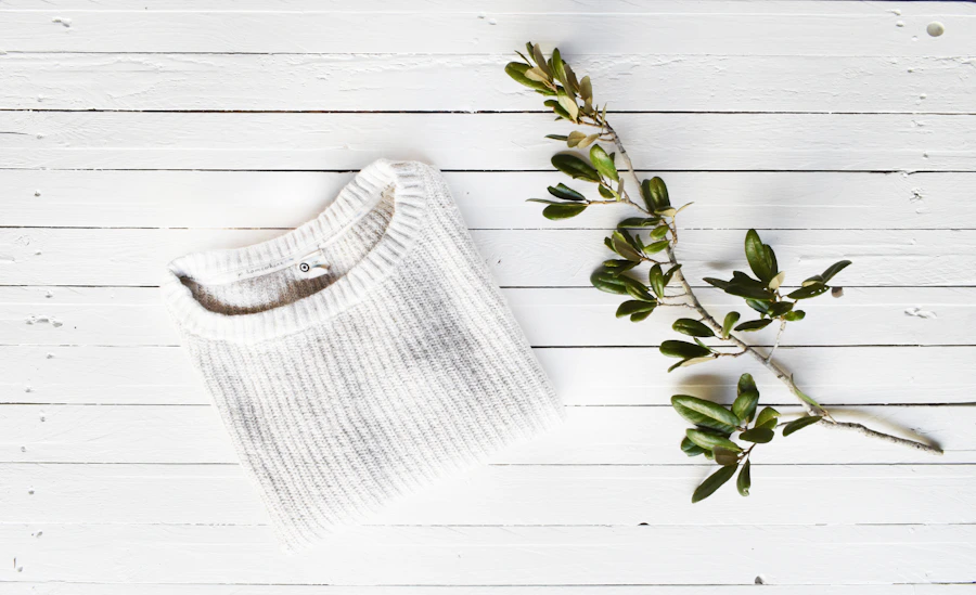 Folded knit sweater beside a green branch