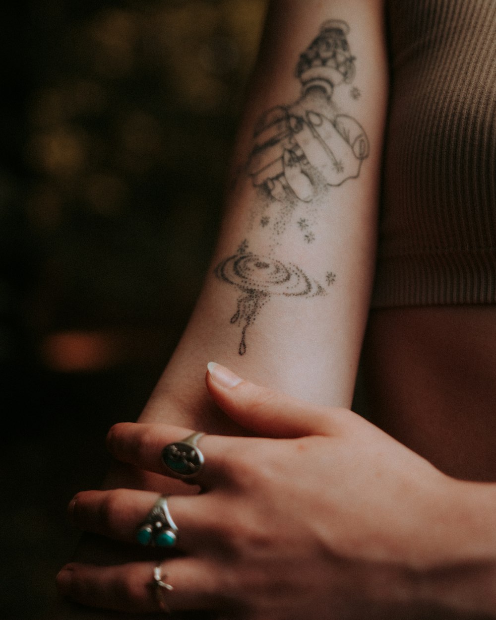 person with black and blue skull tattoo wearing silver ring