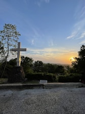 A warm yellow cross illuminated by soft sunlight in a peaceful outdoor setting.