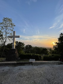 A warm yellow cross illuminated by soft sunlight in a peaceful outdoor setting.
