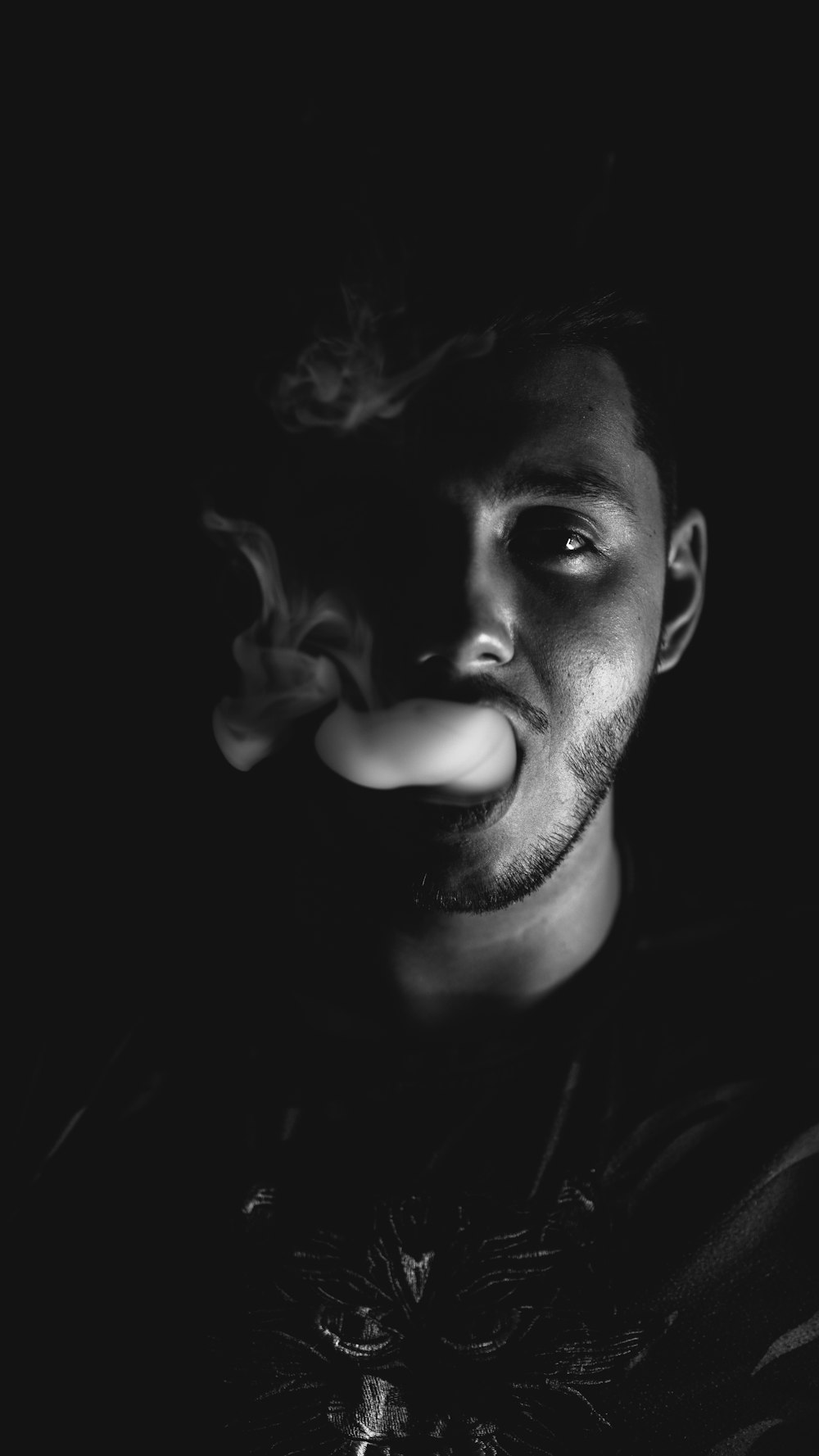 grayscale photo of man with smoke on his mouth