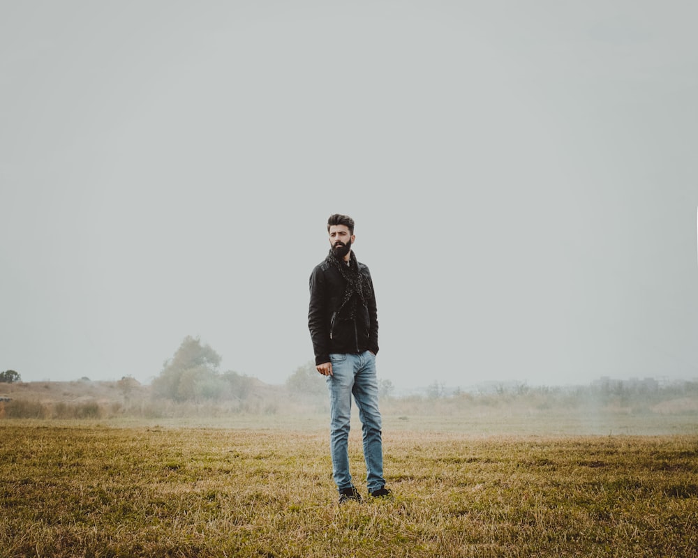 man in black jacket standing on green grass field during daytime