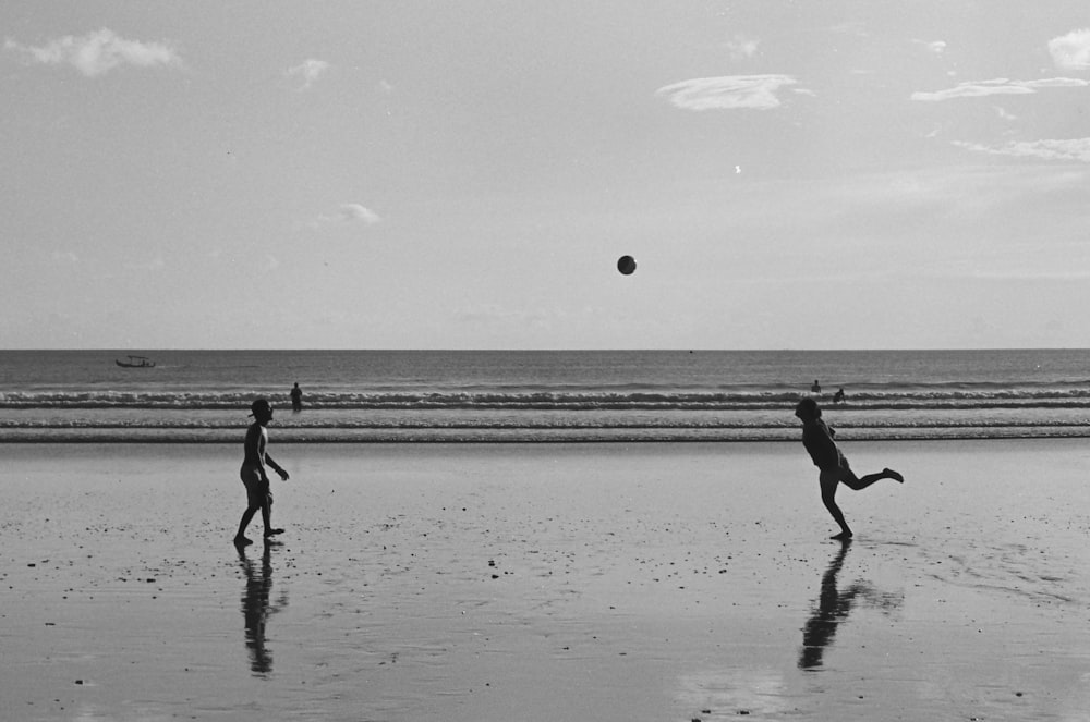 Graustufenfoto von 2 Kindern, die am Strand spielen