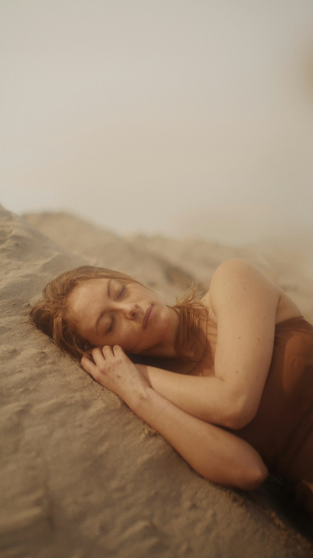 woman lying on brown sand during daytime