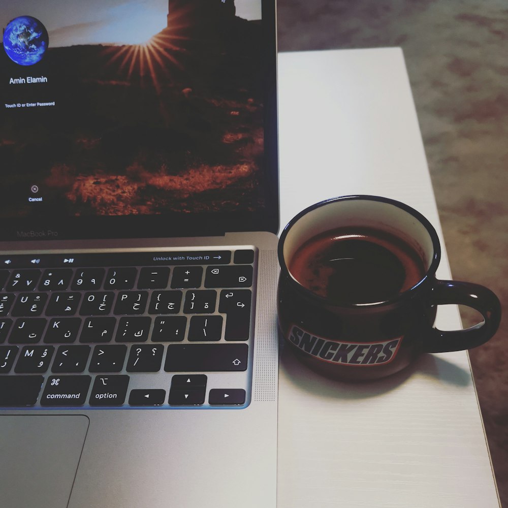 black ceramic mug on macbook pro