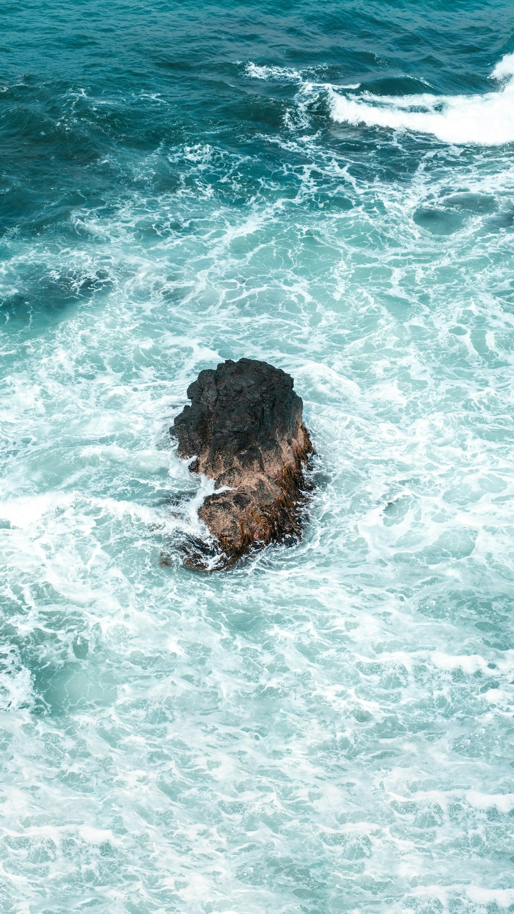 brown rock formation on body of water during daytime