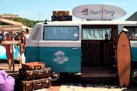 blue and white van with surfboard for a surf trip on the beach