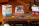 A smiling woman holding a completed custom photo puzzle with a keepsake box on a cozy living room table.