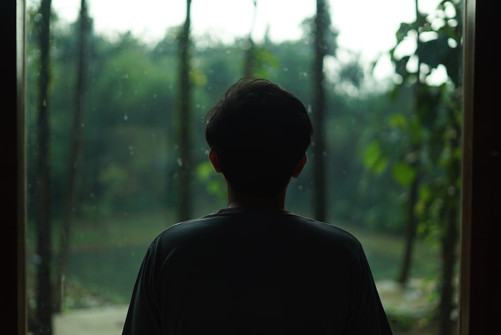 man in black crew neck shirt standing in the forest during daytime