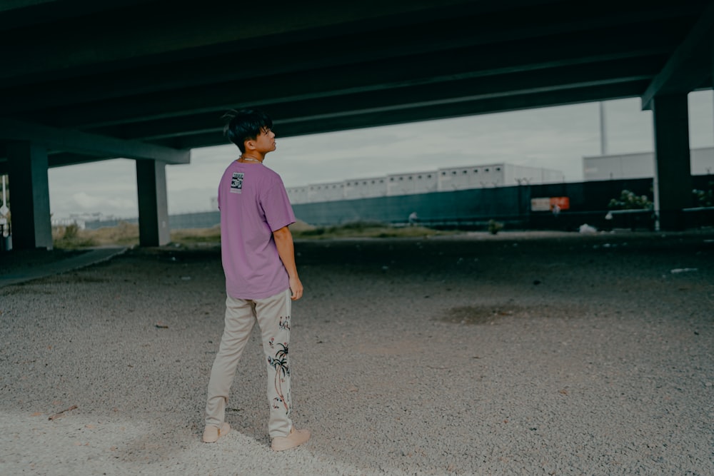 woman in purple shirt and white pants standing on gray concrete floor