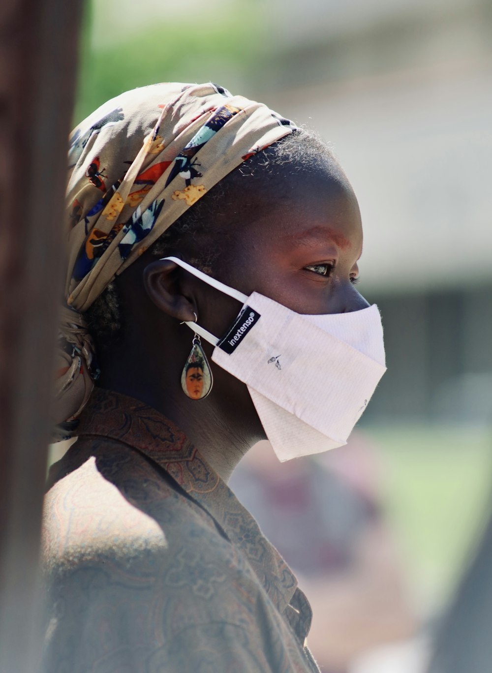 woman in brown and white floral shirt wearing white mask