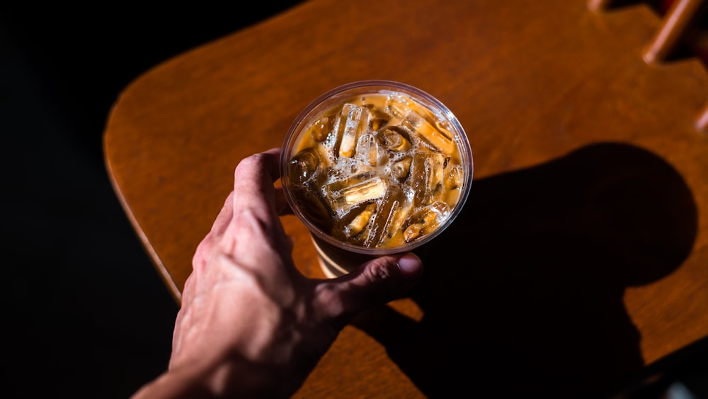 person holding clear glass container with cigarette butts