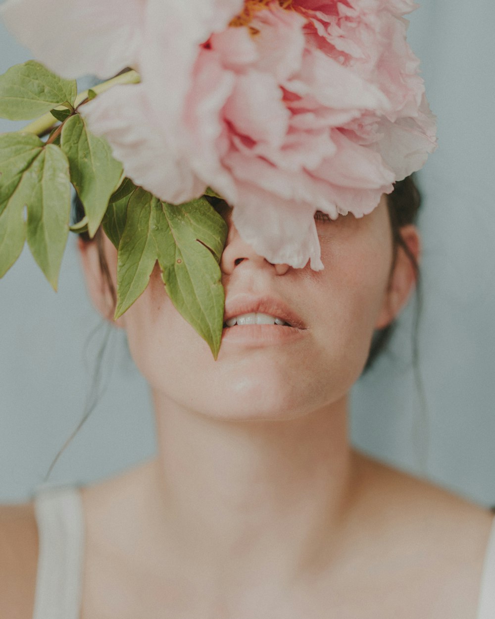 woman in white tank top with white and pink rose on her ear