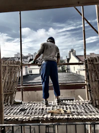 A construction worker reviewing blueprints on a building site with a city skyline in the background.