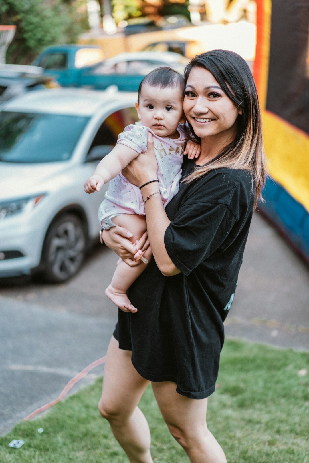 woman in black dress carrying girl in pink dress