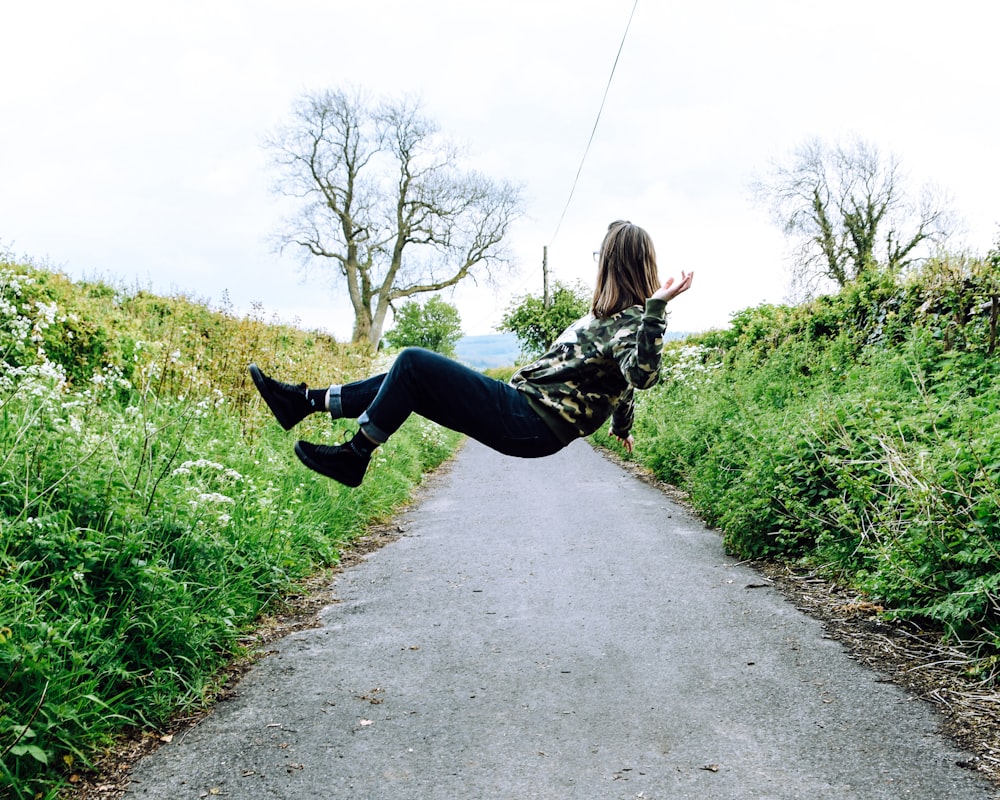 girl in hoodie and blue denim jeans levitating on gray concrete lane during daytime