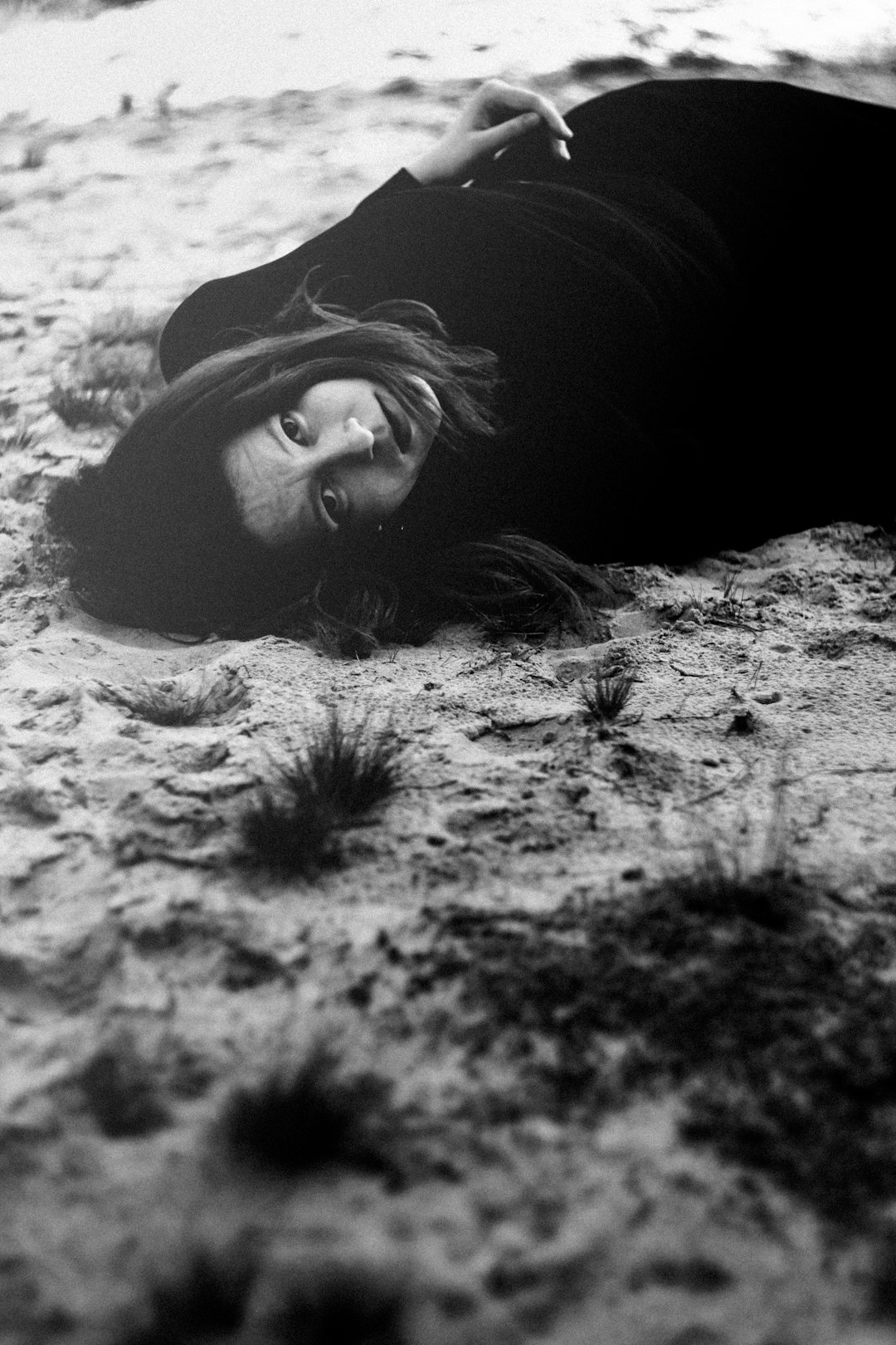 woman lying on sand in grayscale photography