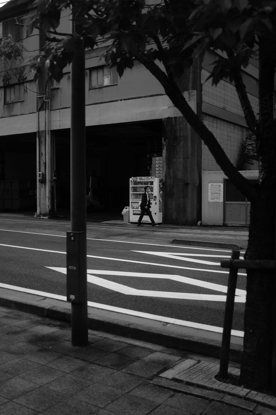 grayscale photo of man walking on sidewalk