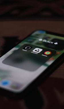 A close-up view of a smartphone screen displaying three app icons inside a folder labeled 'BLACK'. The visible apps are the Watch, Unsplash, and Fitness apps.