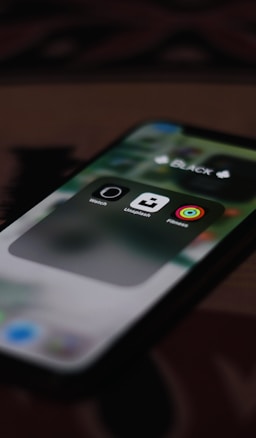 A close-up view of a smartphone screen displaying three app icons inside a folder labeled 'BLACK'. The visible apps are the Watch, Unsplash, and Fitness apps.